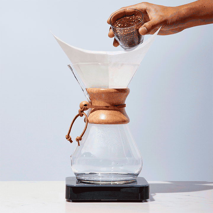 Ground coffee is poured into a Chemex
