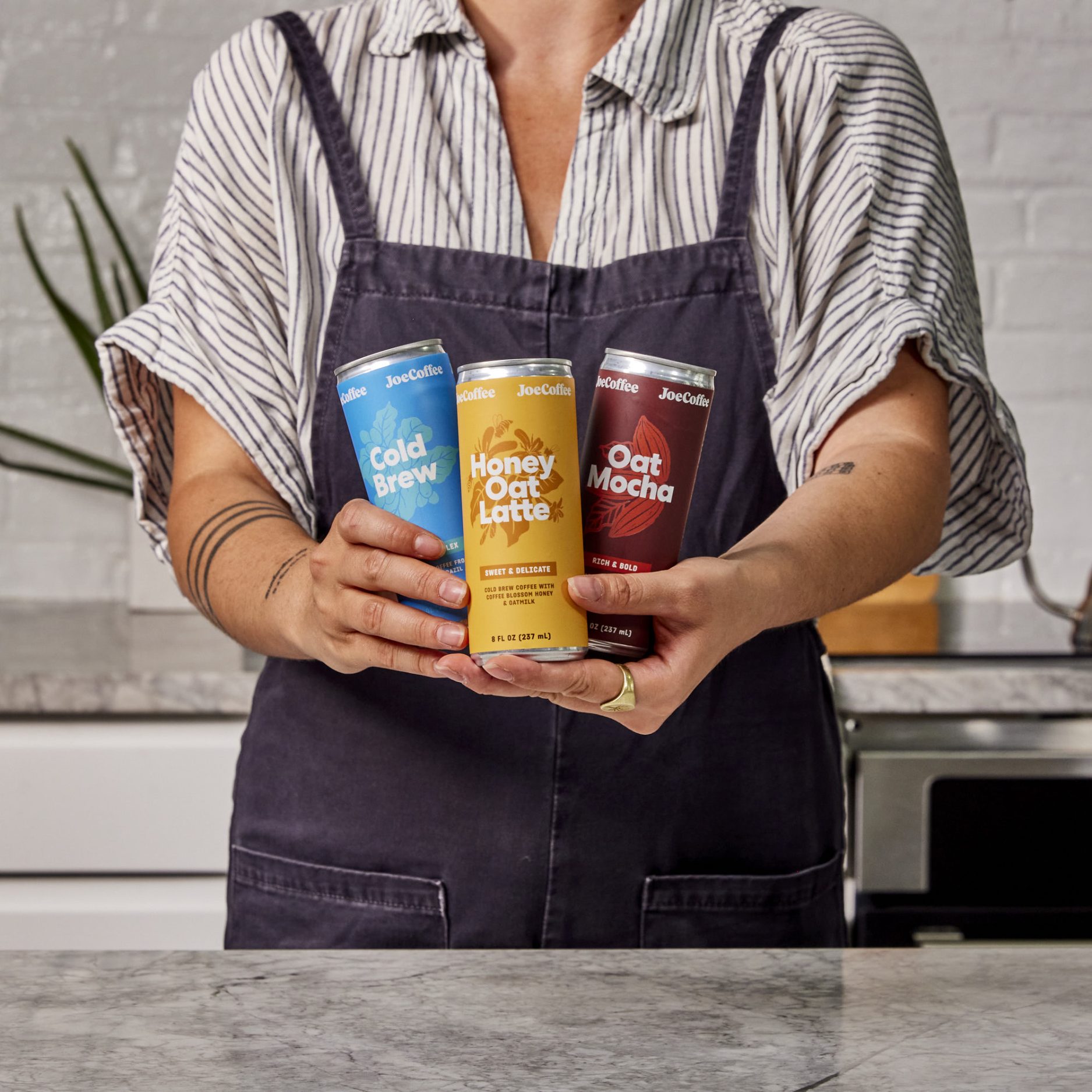 Arms holding three Cold Brew Collection cans